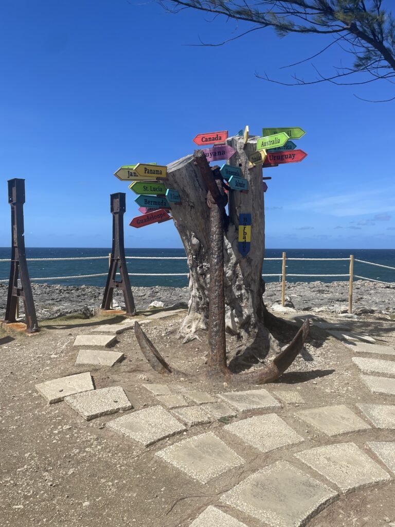 Directional signs behind an anchor on the cliff in Barbados
