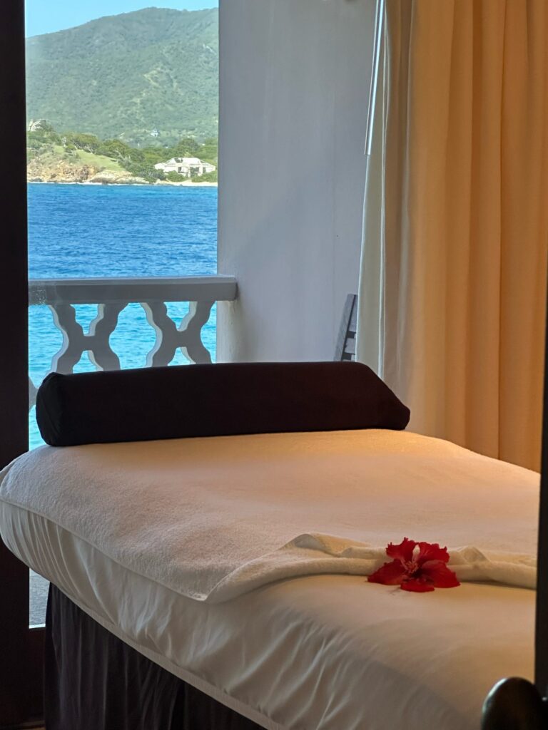 Massage table in a spa room with the view of the ocean out the window